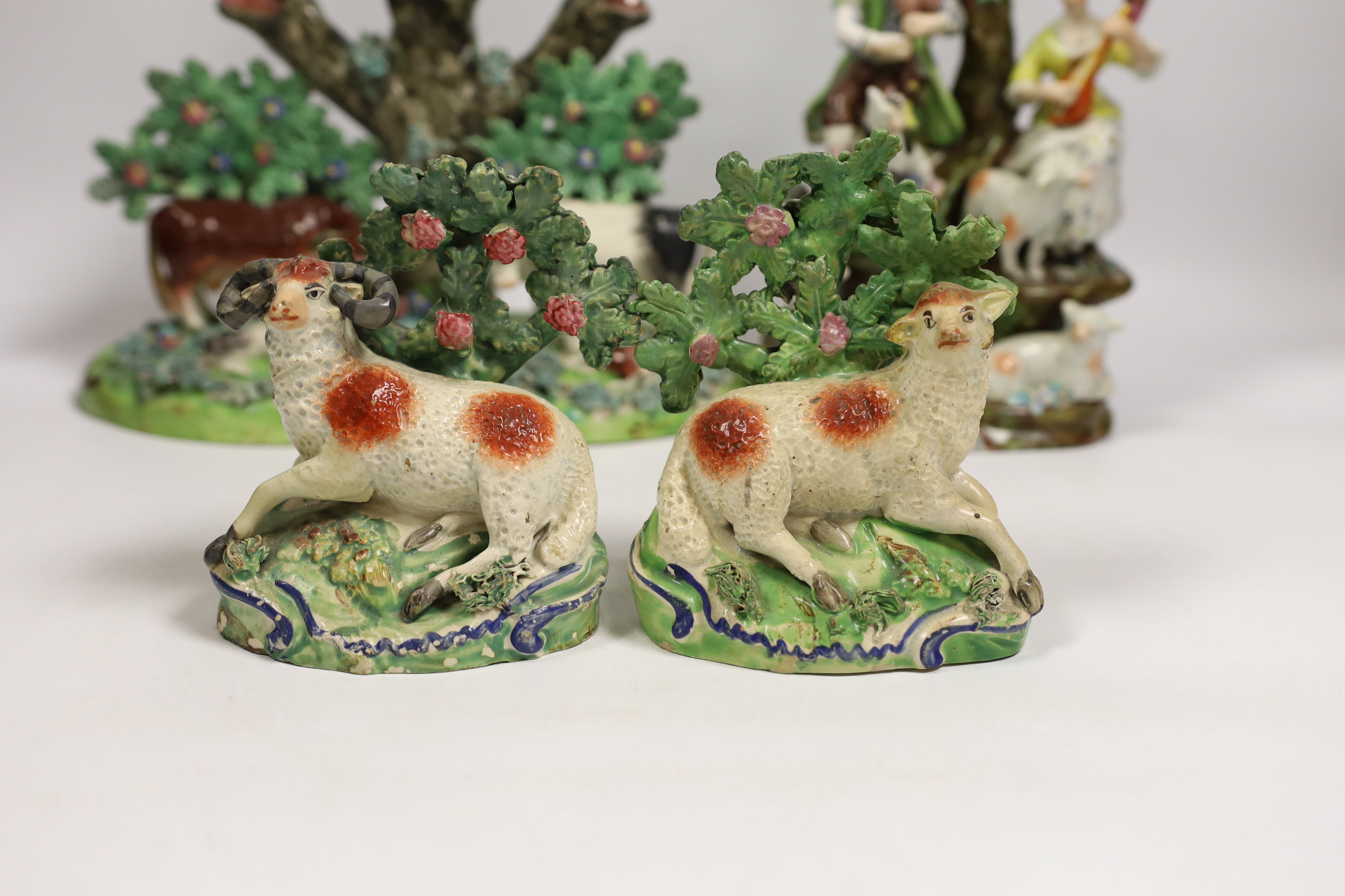 Four 19th century Staffordshire figurative groups; two musicians with sheep, etc. cows with calves group, and a pair of sheep and ram stamped ‘salt’, tallest 27cm